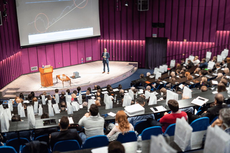 A theatre of people listening to a speaker at a business event